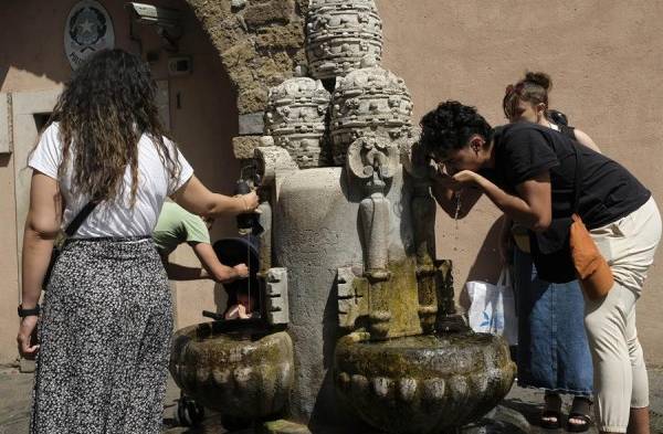 Varias personas se refrescan en una fuente en Roma, Italia.