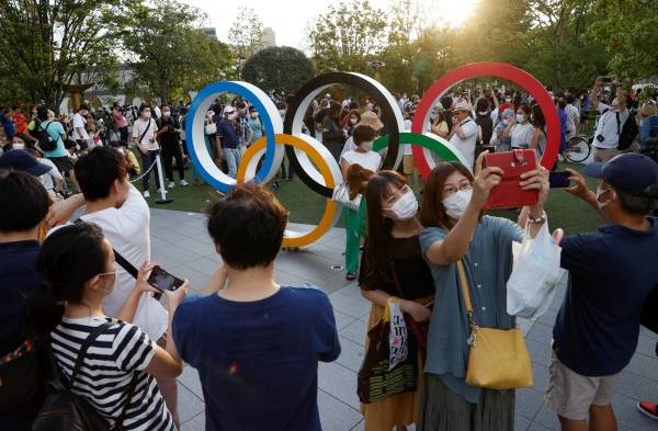 Varios curiosos se congregan delante del Estadio Olímpico, en Tokio.