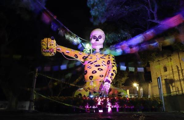 Visitantes observan figuras de calaveras gigantes, el 20 de octubre de 2022, en las calles del municipio de Atlixco, estado de Puebla (México).