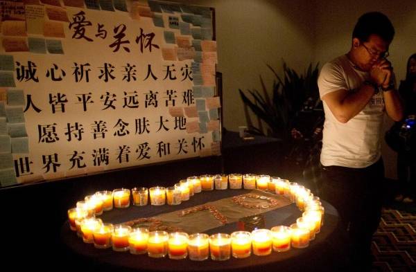 Familiares de los pasajeros chinos a bordo del vuelo 370 de Malaysia Airlines, ora cerca de las velas antes de una reunión informativa con funcionarios malasios en un hotel en China.