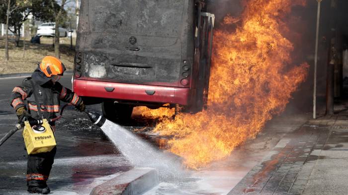 Un bombero extingue un autobús en llamas, incendiado por grupos del crimen organizado en respuesta a un operativo en Jalisco para detener a un objetivo de seguridad prioritario, en una de las principales avenidas de Zapopan, Jalisco, México, el 22 de febrero de 2026.