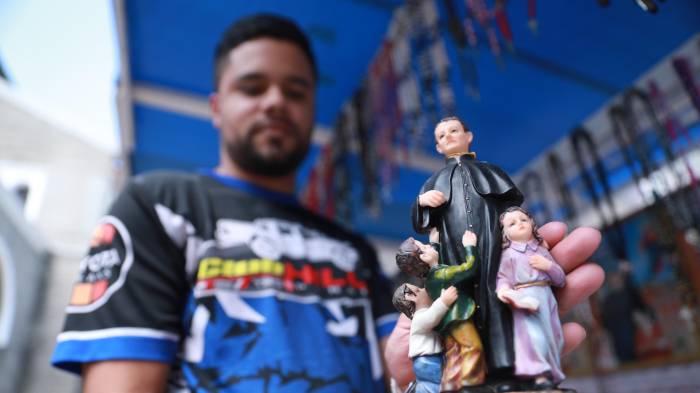 Devotos muestran estampas y figuras de Don Bosco.