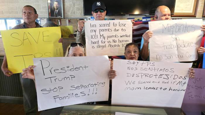 Migrantes beneficiados con el Estatus de Protección Temporal (TPS) sostienen carteles durante una rueda de prensa este lunes.