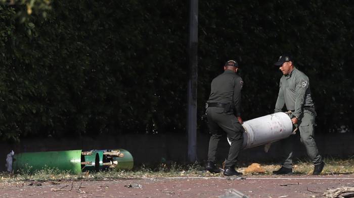 Policías mueven cilindros hallados en la zona del atentado tras una explosión en inmediaciones de la Escuela Militar de Aviación Marco Fidel Suárez este jueves, en Cali (Colombia).