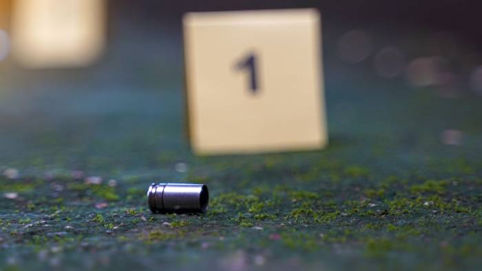 Bullet casings fall on cement floor and blurred background of evidence number sign at shooting scene. Concept of investigation, forensics, evidence, forensic science.