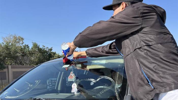 Migrantes venezolanos limpian el parabrisas de un carro en una avenida de la ciudad de Aurora (Estados Unidos).