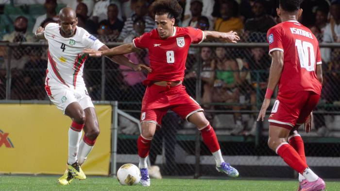 Dion Malone (i) de Surinam disputa el balón con Adalberto Carrasquilla de Panamá en un partido por las eliminatorias a la Copa Mundial 2026.