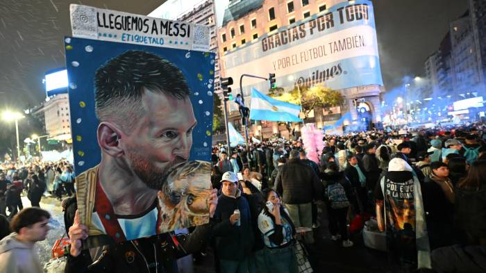 Un aficionado argentino sostiene un dibujo de Lionel Messi besando el trofeo de la Copa del Mundo en el Obelisco, tras la derrota.