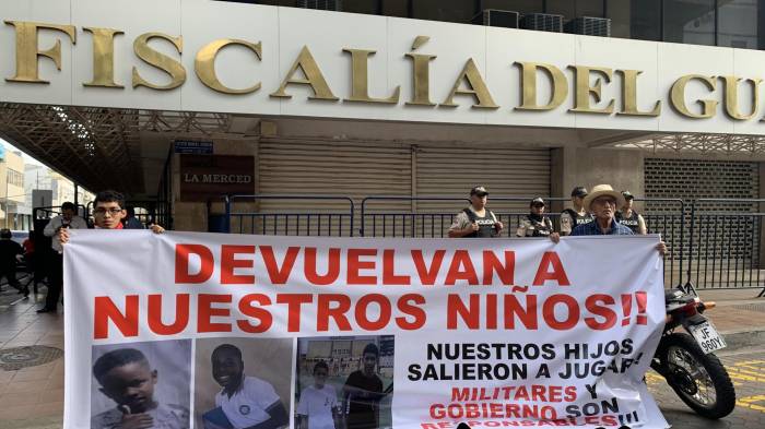 Fotografía del 23 de diciembre de 2024 que muestra a familiares de los menores desaparecidos con un cartel en los exteriores de la Fiscalía Provincial del Guayas en Guayaquil (Ecuador). EFE/Cristina Bazán