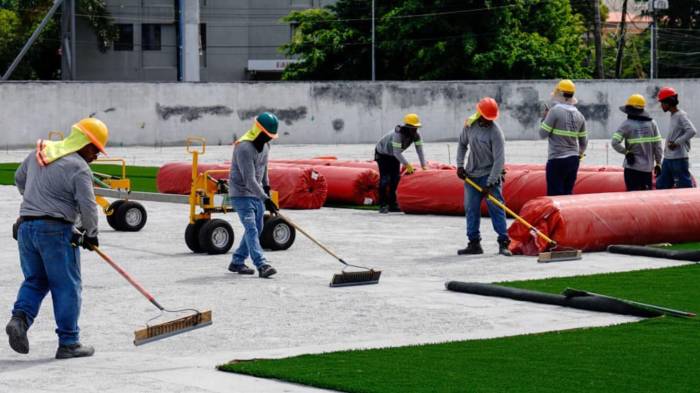 Obreros y técnicos colocan el moderno césped sintético fabricado en Alicante, España.