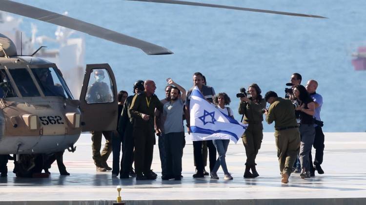 El rehén israelí liberado Nimrod Cohen posa con una bandera israelí tras su llegada al helipuerto del Hospital Ichilov en Tel Aviv.