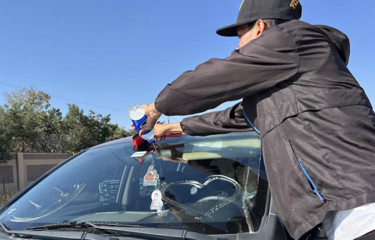 Migrantes venezolanos limpian el parabrisas de un carro en una avenida de la ciudad de Aurora (Estados Unidos).