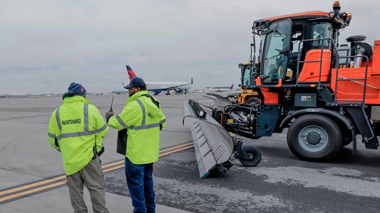 Funcionarios con equipos para remover nieve y hielo.