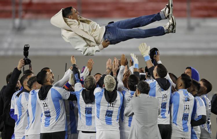 Jugadores de Argentina lanzan a Ángel di María (arriba) previo a un partido de las eliminatorias sudamericana para el Mundial 2026.