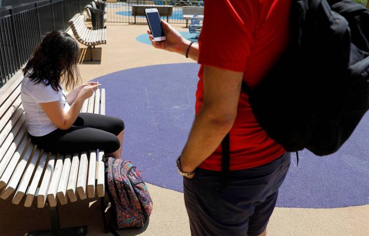 Fotografía de archivo en donde se ven jóvenes que usan sus teléfonos en un parque.