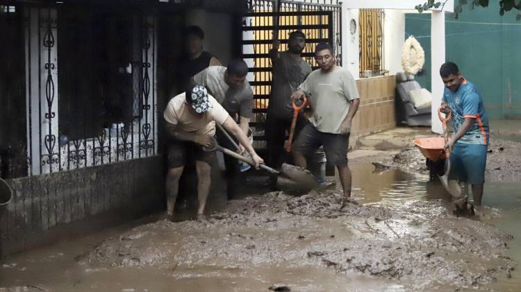 Habitantes de las zonas afectadas por las fuertes lluvias retiran lodo de sus viviendas este domingo, en Huauchinango (México).