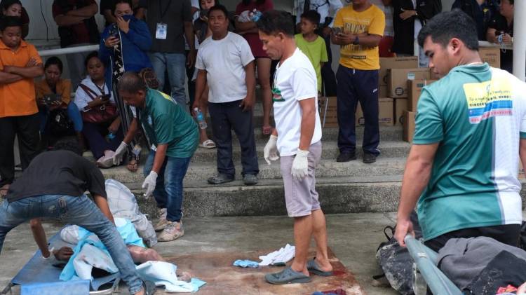Un grupo de filipinas con una víctima del terremoto que azotó el archipiélago.