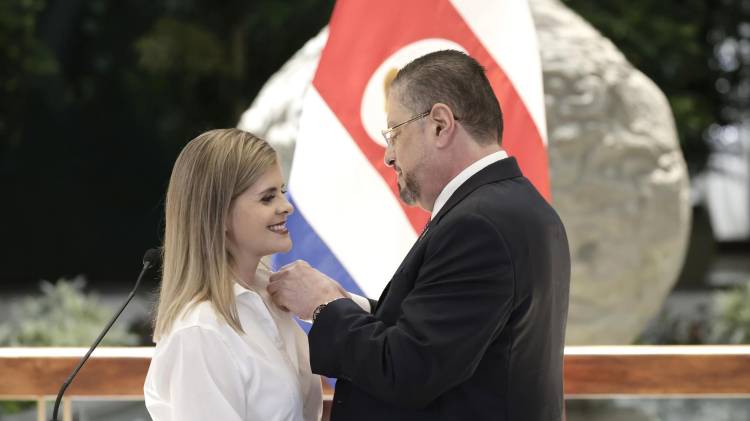 El presidente de Costa Rica, Rodrigo Chaves (d), pone una insignia de ministra de Presidencia a la presidenta electa de Costa Rica, Laura Fernández.