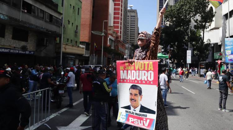 Una persona sostiene un cartel con la imagen del presidente de Venezuela, Nicolás Maduro, durante una marcha del chavismo este domingo, en Caracas (Venezuela). EFE/ Ronald Peña R