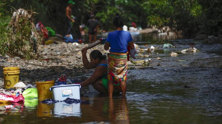 Fotografía de archivo en donde se ven dos mujeres que lavan ropa en un río contaminado con basura en la frontera entre Panamá y Colombia. EFE/ Bienvenido Velasco