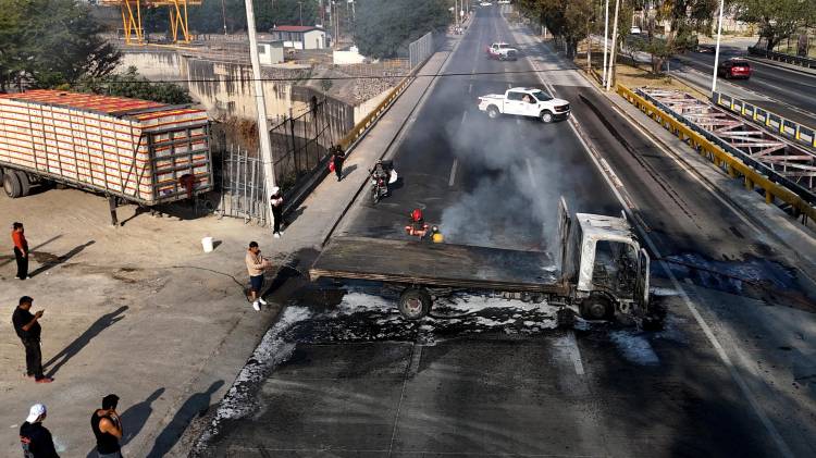 Un hombre extingue un camión en llamas, incendiado por grupos del crimen organizado en respuesta a un operativo en Jalisco para detener a un objetivo de seguridad prioritario, en una de las principales avenidas de Zapopan, Jalisco, México, el 22 de febrero de 2026.
