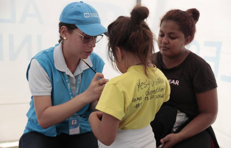 Una funcionaria de Aldeas Infantiles pinta la mano de una niña el 8 de julio de 2024 en Turbo (Colombia).