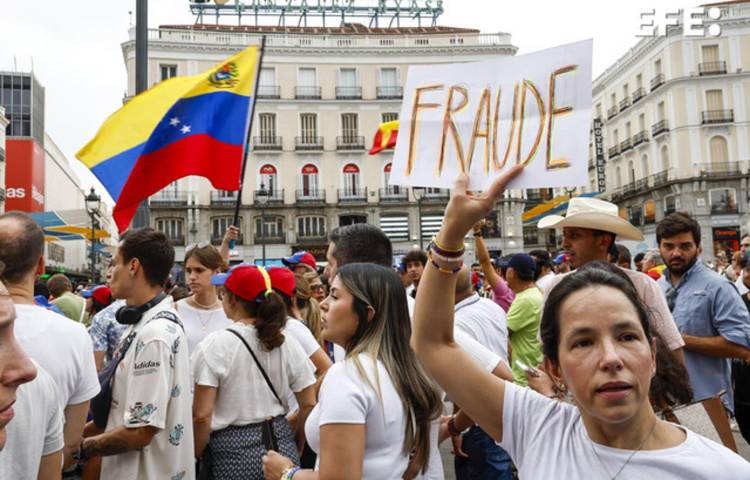 Una mujer sostiene una pancarta en la manifestación convocada por la oposición venezolana un día después de las elecciones en el país, este lunes en Madrid.