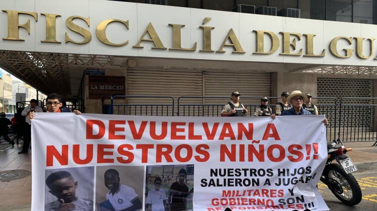 Fotografía del 23 de diciembre de 2024 que muestra a familiares de los menores desaparecidos con un cartel en los exteriores de la Fiscalía Provincial del Guayas en Guayaquil (Ecuador). EFE/Cristina Bazán