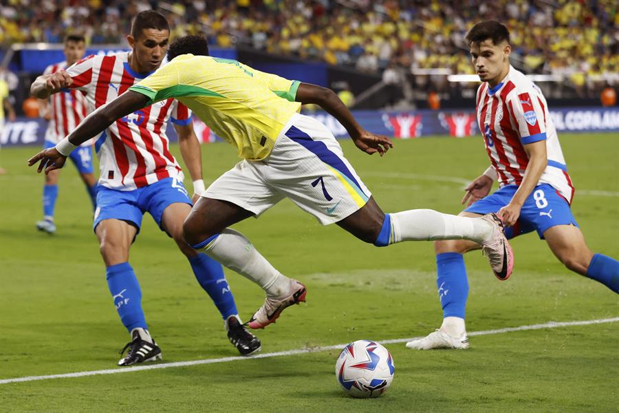 El delantero brasileño Vinicius Junior (C) en acción contra el defensor paraguayo Gustavo Velázquez (i) y el centrocampista paraguayo Damian Bobadilla (d) durante la segunda mitad del partido de la Copa América 2024 entre Paraguay y Brasil, en Las Vegas, Nevada, EE.UU.
