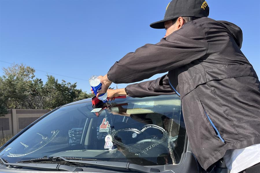 Migrantes venezolanos limpian el parabrisas de un carro en una avenida de la ciudad de Aurora (Estados Unidos).