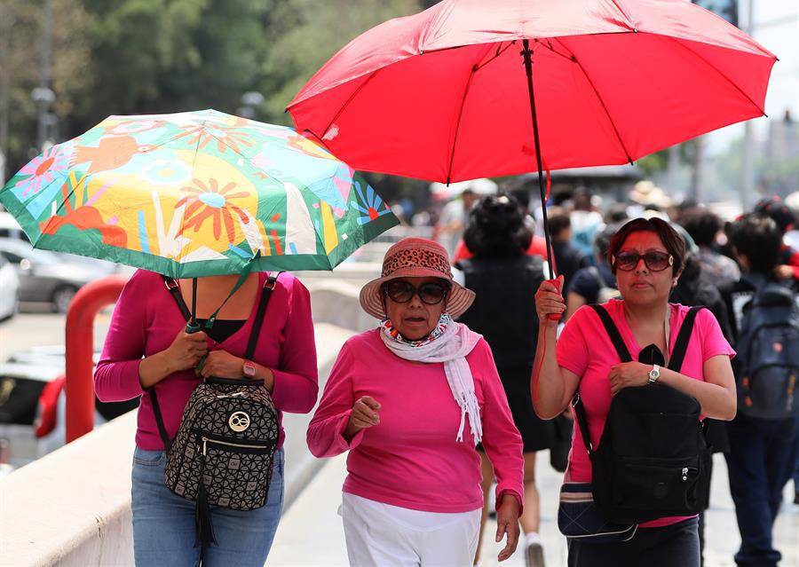 Mujeres sostienen sombrillas para protegerse del sol el 19 de mayo de 2024, en la Ciudad de México.